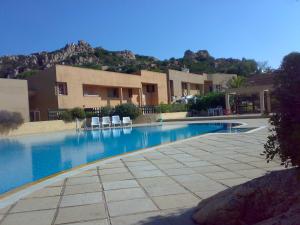 a swimming pool with chairs in front of a building at Casa Gialla in Costa Paradiso