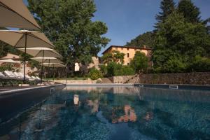 a swimming pool with umbrellas and a house in the background at Relais Corte Rodeschi in Camaiore +59 photos