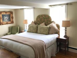 a bedroom with a bed with a chair and two windows at Admiral Farragut Inn in Newport