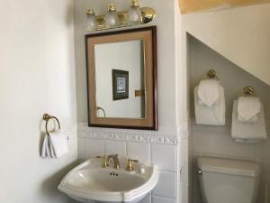 a bathroom with a sink and a mirror and a toilet at Cleveland House Inn in Newport