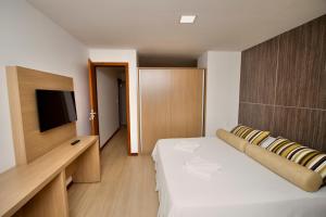 um quarto de hotel com uma cama e uma televisão em Hotel Atlântico em Guarapari