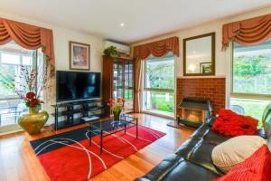 a living room with a couch and a television at Lakeside Cottage Luxury B&B in Mount Dandenong