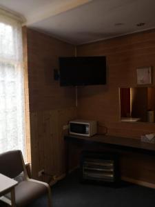 a room with a tv and a table with a microwave at Jasper Motor Inn in Adelaide
