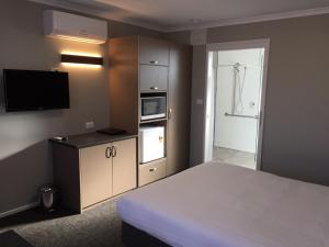 a hotel room with a bed and a tv and a bathroom at Eaglehawk Motel Bendigo in Bendigo