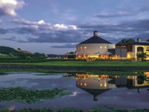 Craggy Range Luxury Vineyard Retreat في هافلوك الشمالية: مبنى ابيض كبير بجوار بحيرة في الليل