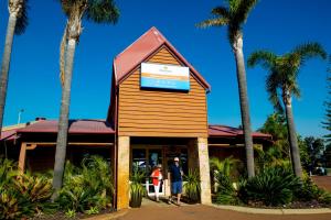two people standing in front of a building with palm trees at Discovery Parks - Bunbury Foreshore in Bunbury