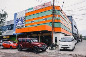 Reddoorz Plus near Makassar Town Square في ماكاسار: مبنى فيه سيارات تقف امامه