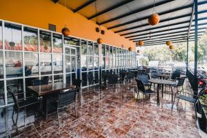 un restaurant vide avec des tables, des chaises et des fenêtres dans l'établissement RedDoorz Plus near Sultan Hasanuddin Airport, à Makassar