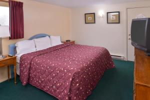 a hotel room with a bed and a flat screen tv at Red Carpet Inn Pulaski in Pulaski