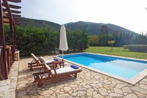 a swimming pool with two chairs and an umbrella at Echinades Resort in Vasiliki