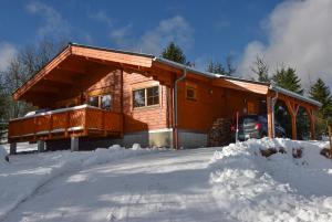 ein Blockhaus im Schnee mit einem Auto vor dem Haus in der Unterkunft Erzgebirgsholzhaus am Lugstein in Kurort Altenberg
