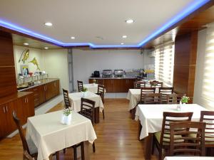 a restaurant with white tables and chairs and a kitchen at Lifos Hotel in Kayseri