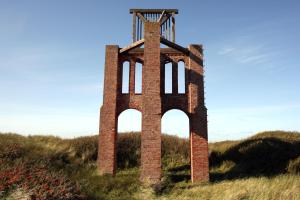 une grande tour en briques au milieu d'un champ dans l'établissement BORKUMUNTERKUNFT - WOH3 - IM HERZEN DER INSEL, à Borkum