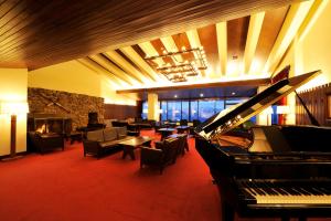 a living room with a piano and a fireplace at Akakura Kanko Hotel in Myoko