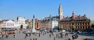 un grupo de personas caminando por una ciudad con edificios en NOCNOC - Le Petit National, en Lille