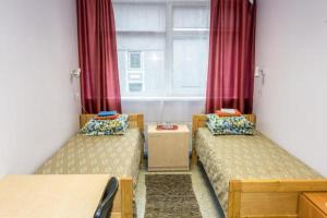 Habitación con 2 camas y ventana con cortinas rojas. en Guesthouse Rehab en Tartu