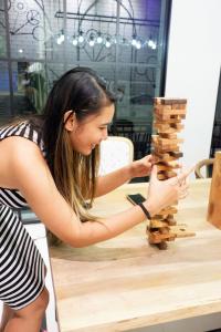 a young woman playing with a wooden block tower at Bedspread Hostel in Bangkok