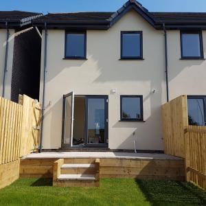 a white house with a wooden fence at Bright modern house beside Snowdonia in Llanfairfechan