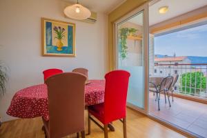 茨雷斯Apartment Vesna的一间带红色桌椅的用餐室和一个阳台