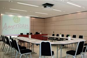a conference room with tables and chairs and a screen at American Hotel in Pozzuoli