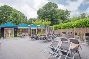 un patio con sedie, tavoli e ombrelloni di Chalet Vakantie Wageningen Veluwe a Wageningen