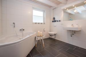 ein Badezimmer mit einer Badewanne, einem Waschbecken und einem WC in der Unterkunft Ferienhaus Hafenkante mit Sky in Nordhorn
