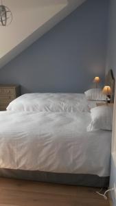 a white bed in a bedroom with a blue wall at COTTAGE DE L'ANCRE in Albert