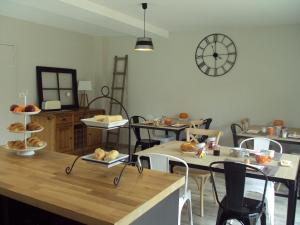 a room with tables and chairs and a clock on the wall at Tartine & Polochon in Longué