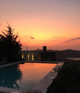 a swimming pool with a sunset in the background at Aigaion House in Otziás