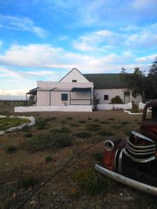 a white house with a truck in front of it at Silwerkaroo Gastehuis in Beaufort West