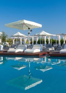 a pool with white lounge chairs and an umbrella at The Blue Ivy Hotel & Suites in Protaras