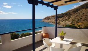 een balkon met een tafel en stoelen en de oceaan bij Big Blue Apartments in Myrtos