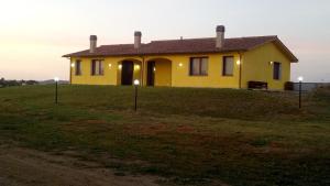 uma casa amarela no topo de uma colina relvada em Il Chiosco Giallo em Capalbio