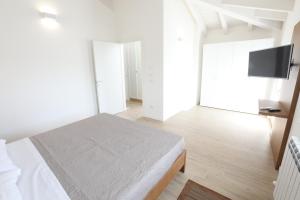 a white bedroom with a bed and a flat screen tv at Casa San Valentino in Bussolengo