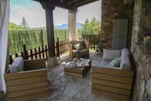 een patio met een bank en stoelen aan een stenen muur bij Nature Rural in Berzosa del Lozoya