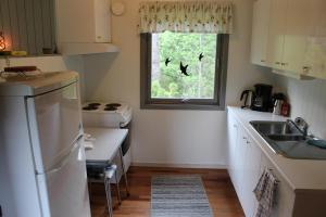 eine Küche mit einem weißen Kühlschrank und einem Fenster in der Unterkunft Bergheim Two-Bedroom Cottage in Birkeland