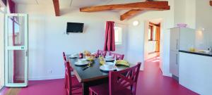 a dining room with a table with chairs and a kitchen at VVF Gers Gascogne in Mauvezin