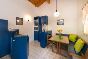 una cocina con armarios azules y una mesa con una almohada verde en Village Vacances Leo Lagrange, en Montbrun-les-Bains