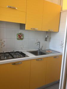 - une cuisine avec des placards jaunes et un évier dans l'établissement Casa Michela, sea-view apartments, à Trabia