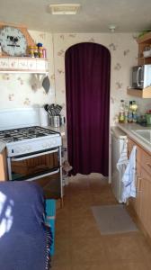 a kitchen with a stove and a purple curtain at Mobil home vacances in Plouguerneau