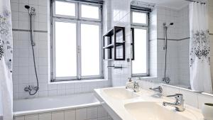 a white bathroom with two sinks and a tub and windows at Penzion Dvořákova in Brno