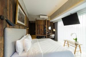 a bedroom with a white bed and a television at ARTOTEL Haniman Ubud in Ubud