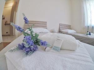 een wit bed met een boeket paarse bloemen erop bij Casa Claudia in La Spezia