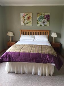 a bedroom with a bed with a purple comforter at Brackenbrae Holiday Cottage in Acharacle