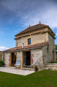 une maison en pierre avec deux chaises et un hamac à l'extérieur dans l'établissement Rataboul, à Puylaroque