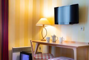 a desk with a lamp and a television on a wall at Hotel Delambre in Paris