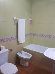 a bathroom with a toilet and a tub and a sink at Hostal Hispalis in Gandul