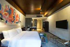 a bedroom with a white bed and a flat screen tv at ARTOTEL Haniman Ubud in Ubud