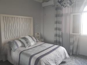 biała sypialnia z łóżkiem i oknem w obiekcie Hostal Hispalis w mieście Gandul