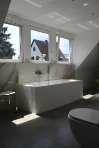 ein weißes Bad mit einer Badewanne und 2 Fenstern in der Unterkunft Landhaus Almyssen in Alsbach